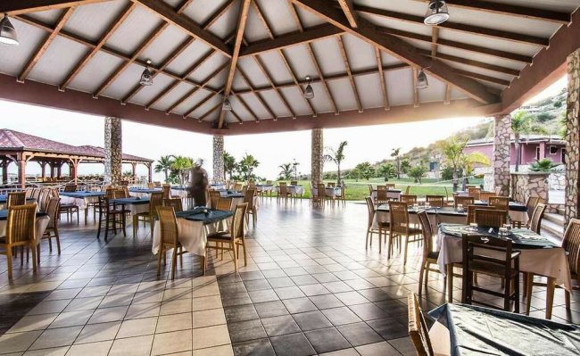 Una sala ristorante esterna con tavoli apparecchiati vista giardino.