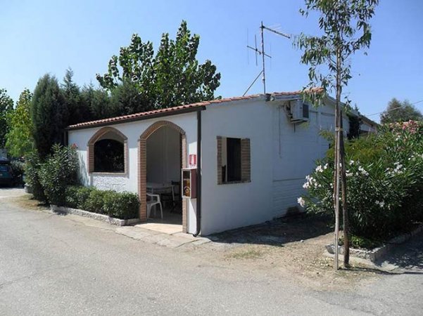 Edificio bianco con tetto spiovente in giardino.