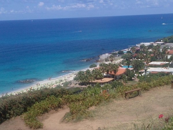 Spiaggia e mare azzurro con case lungo la costa.