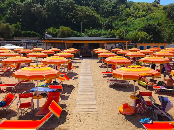 Spiaggia con ombrelloni arancioni e lettini sulla sabbia.