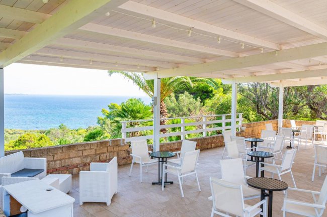 Terrazza con sedie bianche e vista sul mare.