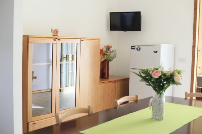 Sala con tavolo, mobile in legno e TV a schermo piatto.