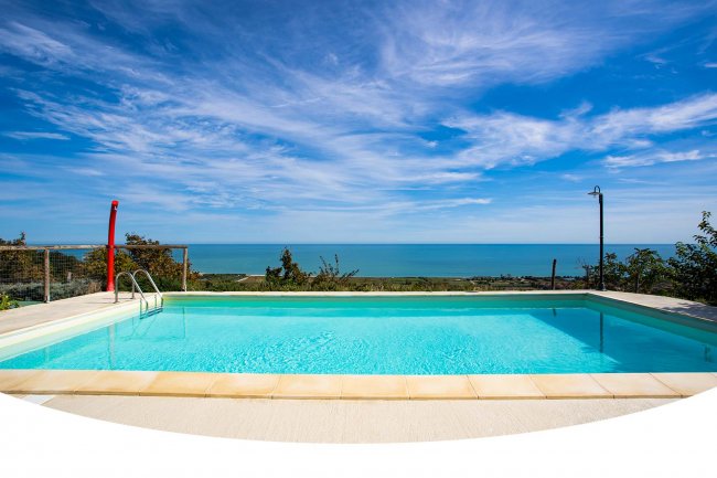 Piscina con vista sull'oceano e cielo sereno.