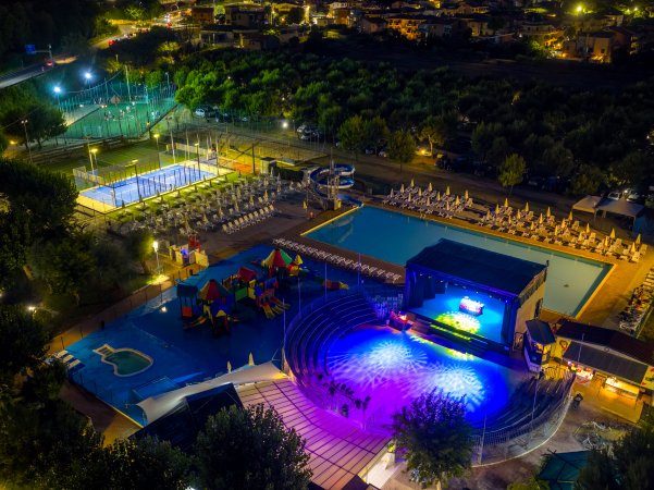 Parco giochi e piscina illuminata di notte.