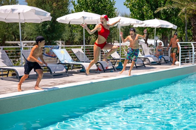 Ragazzi tuffano in piscina da bordo vasca.