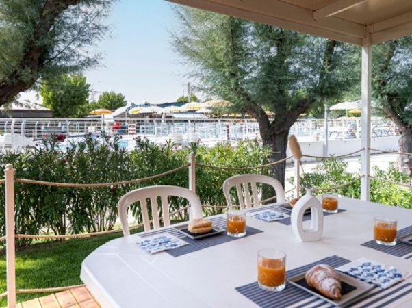 Tavolo esterno apparecchiato vicino alla piscina.