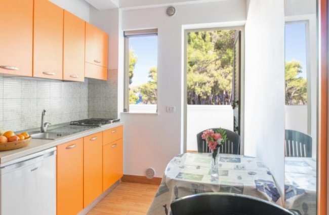 Cucina con mobili arancioni e tavolo apparecchiato.