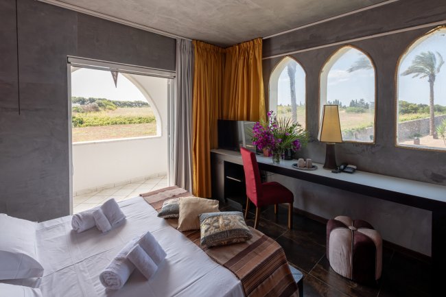 Stanza accogliente con letto, scrivania e grandi finestre ad arco. Vista campagna.