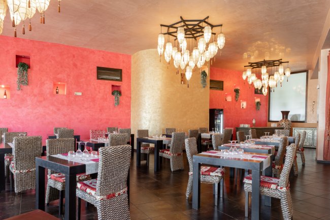 Ristorante con pareti colorate e lampadari eleganti. Tavoli apparecchiati.