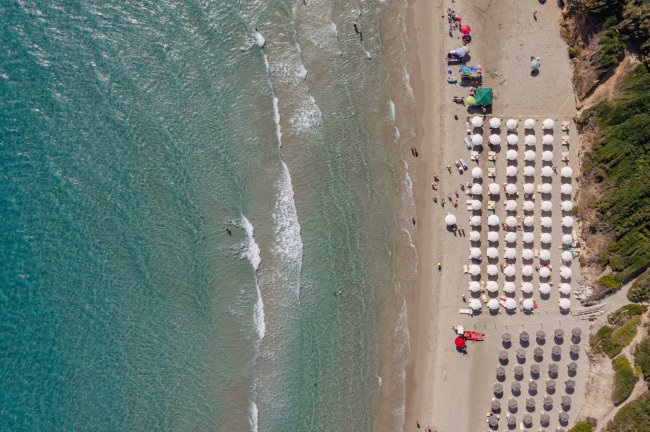 Spiaggia con ombrelloni ordinati vicino al mare.