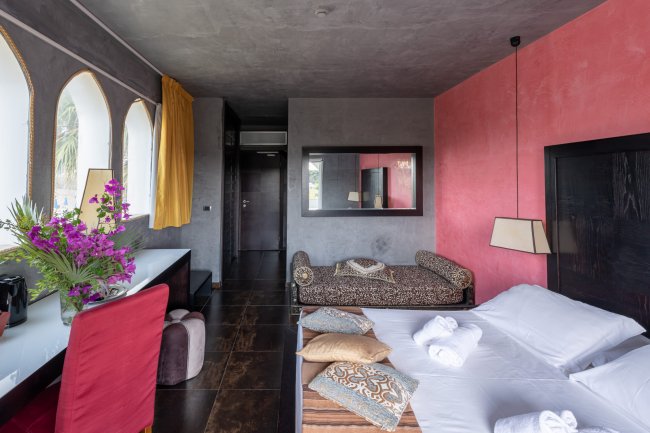 Camera con letto matrimoniale, fiori e finestre ad arco.