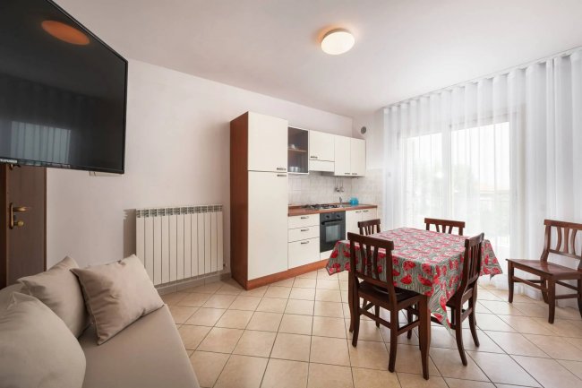 Cucina con tavolo, sedie e TV a parete.