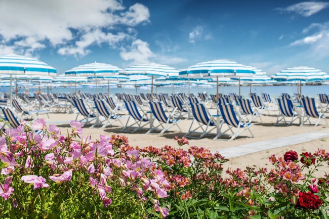 Ombrelloni e lettini a righe blu su una spiaggia.
