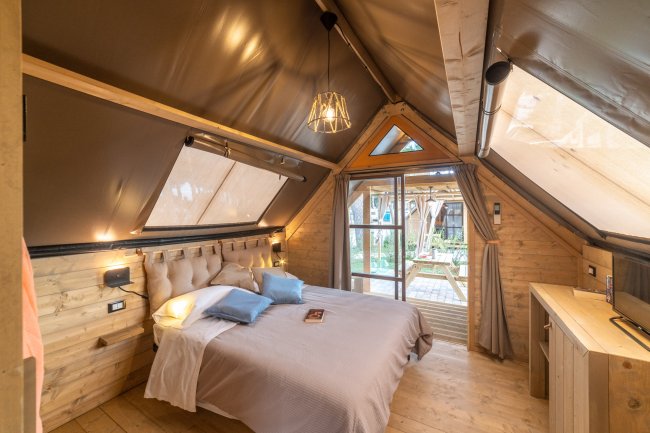 Camera da letto in legno con soffitto inclinato.