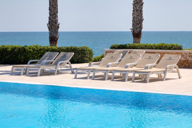 Lettini a bordo piscina con vista mare.