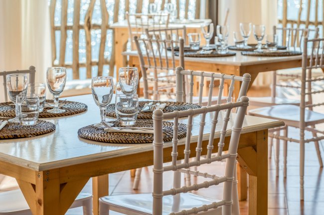 Tavoli apparecchiati in un ristorante con sedie bianche.