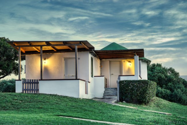 Casetta bianca con tetto verde al tramonto.