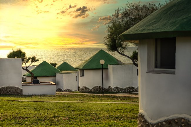 Casette con tetti verdi al tramonto sul mare.