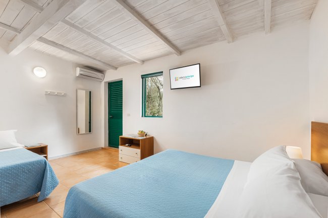 Camera con due letti e TV, arredamento azzurro.