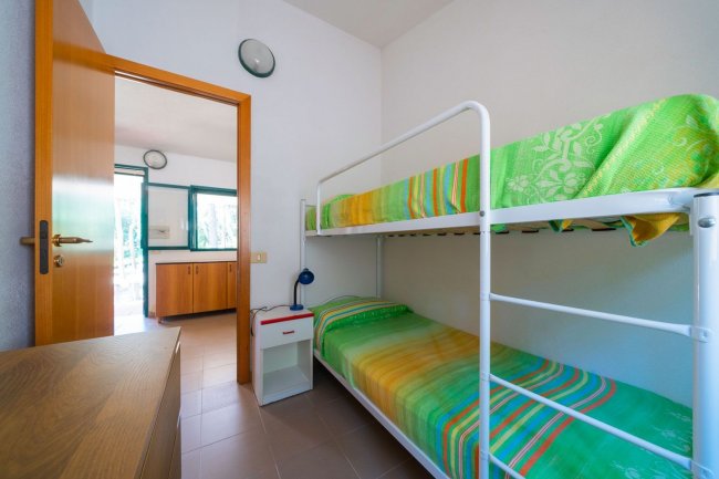 Cameretta con letto a castello e lenzuola verdi.