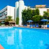 Piscina blu con sedie a sdraio e ombrelloni blu, edificio moderno sullo sfondo.