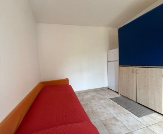 Stanza con divano rosso e frigo.