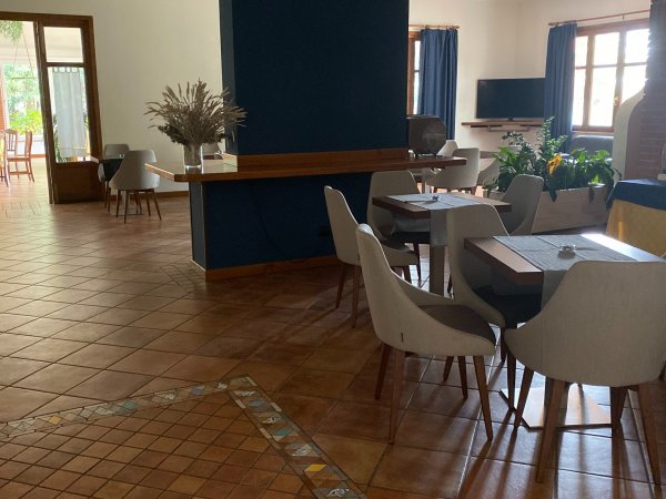 Sala con tavoli e sedie moderne, TV sullo sfondo.