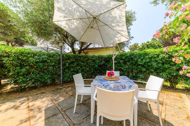 Tavolo all'aperto con sedie bianche.