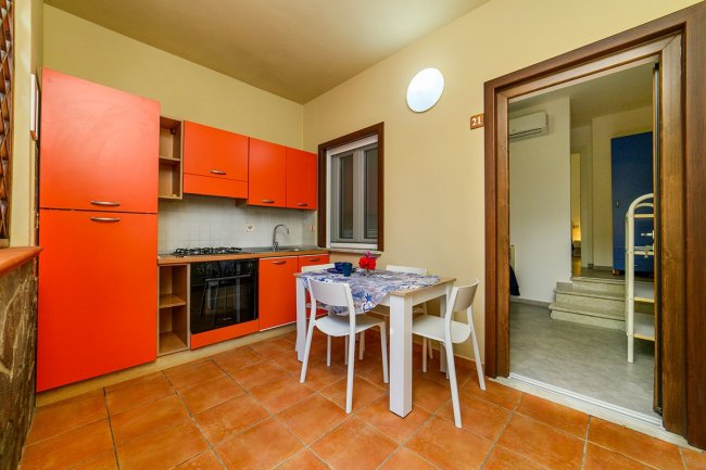 Cucina moderna con mobili arancioni e tavolo bianco.