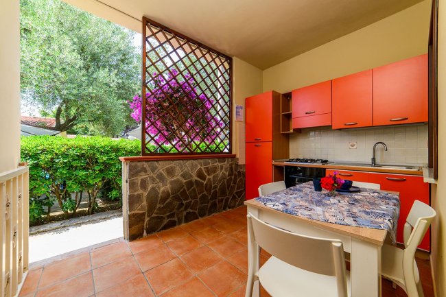 Cucina con mobili arancioni e vista sul giardino.