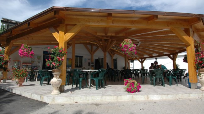 Pergolato con tavoli e sedie verdi.