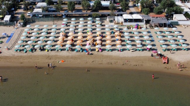Spiaggia con ombrelloni disposti ordinatamente.