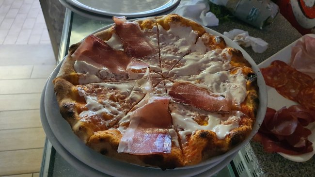 Pizza con fette di prosciutto e formaggio.