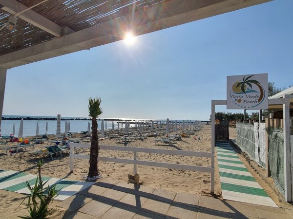Accesso a spiaggia sabbiosa con sedie a sdraio.