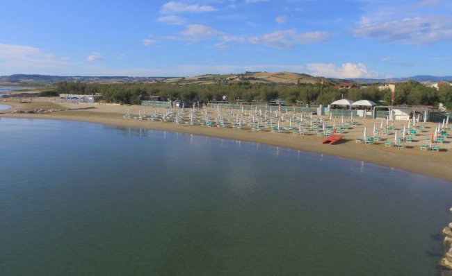 Spiaggia tranquilla con ombrelloni e colline.