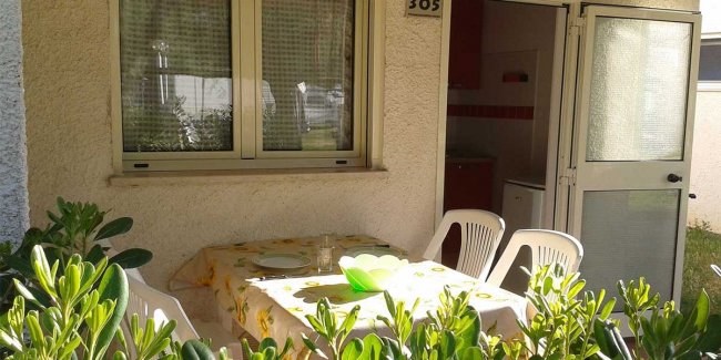 Tavolo con sedie bianche all'esterno di una casa.