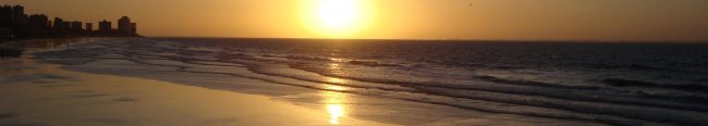 Tramonto su una spiaggia con mare calmo.
