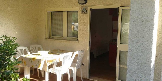 Terrazza con tavolo coperto e sedie di plastica bianche.