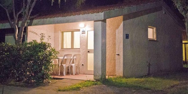 Una casa di notte con veranda e sedie bianche.