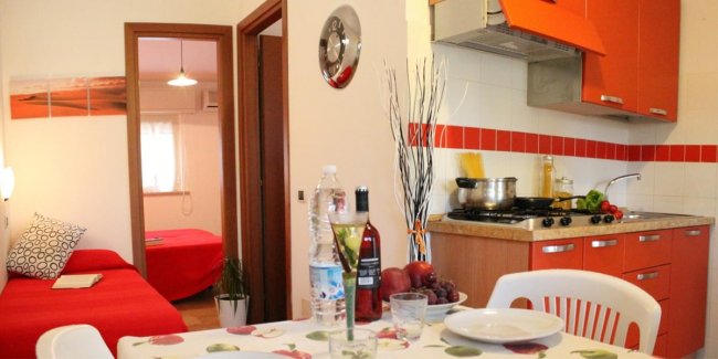 Cucina con tavolo apparecchiato e letto in vista.