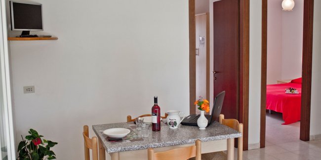 Sala da pranzo con tavolo e sedie, stanza sullo sfondo.