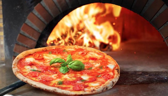 Pizza margherita su pala davanti a forno a legna.