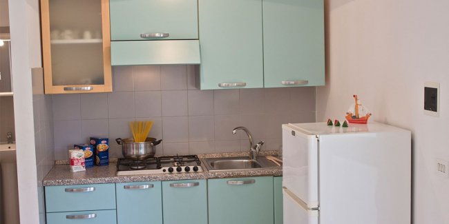 Cucina con mobili azzurri e frigorifero bianco.