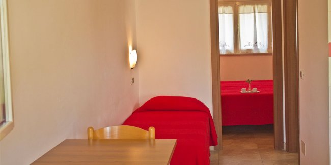 Letto con copriletto rosso in una stanza luminosa.