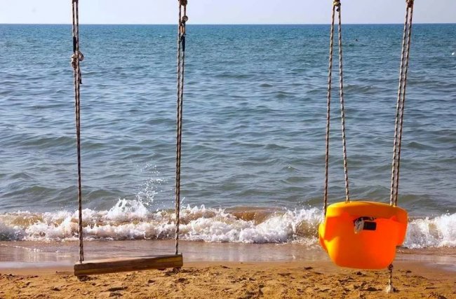 Altalene sulla spiaggia con mare sullo sfondo.