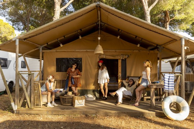 Persone rilassate su una veranda di una tenda nel campeggio.