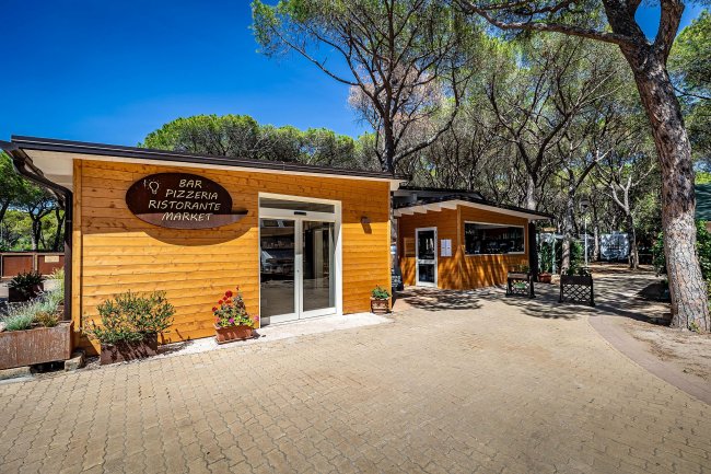 Esterno di un bar e pizzeria in legno tra alberi.