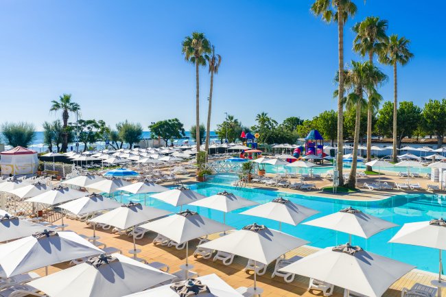 Piscina estiva con ombrelloni bianchi e palme.