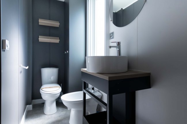 Bagno con lavabo su mobile nero e wc.