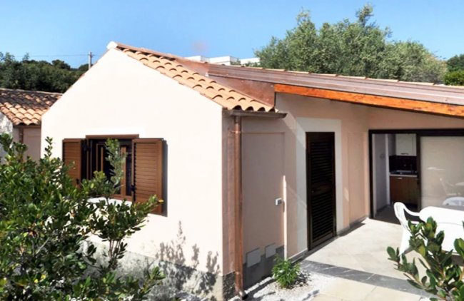 Bungalow con tetto in tegole e giardino.